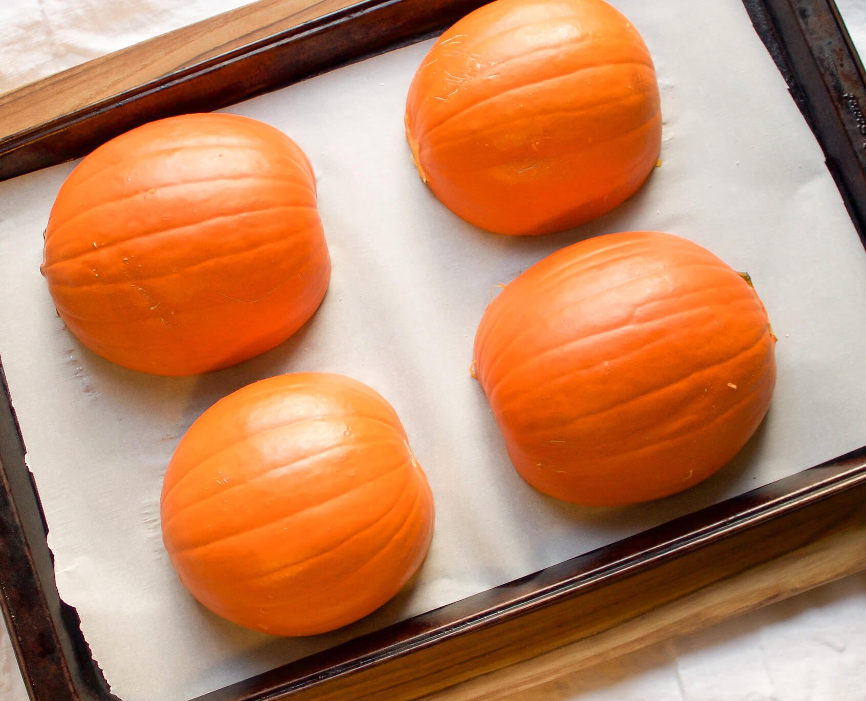 small baking pumpkins on baking sheet with parchment paper face down