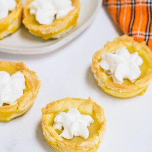 Pumpkin Pie Jello Shots laid on a marble surface, with some of them served on a white plate