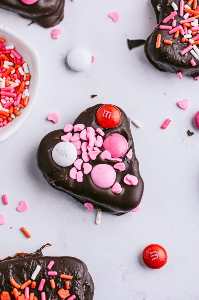 overhead vertical shot of chocolate covered apples with pink, red and white sprinkles for valentine's day