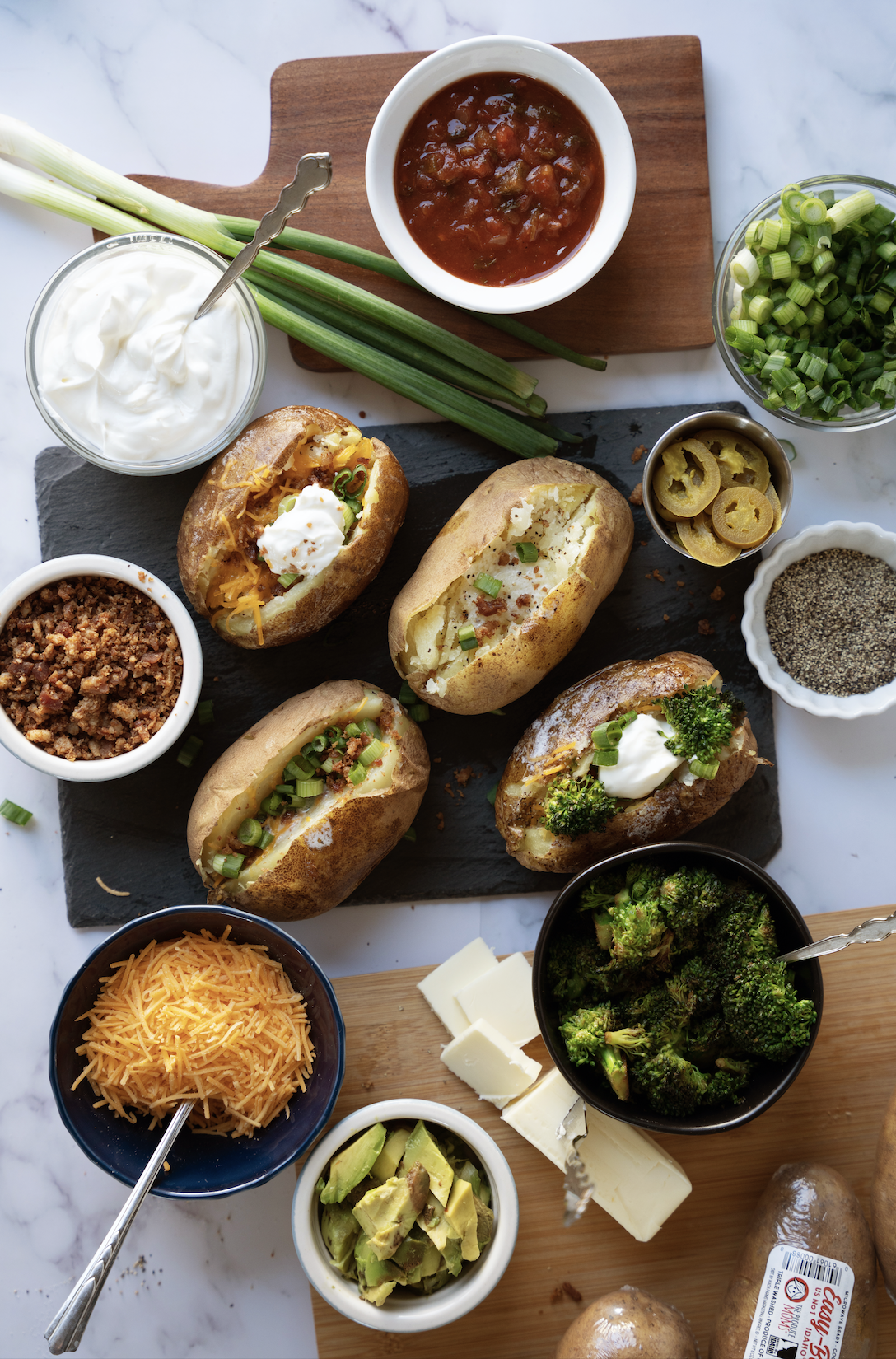 3 Sutffed Baked potatoes surrounded by the toppings