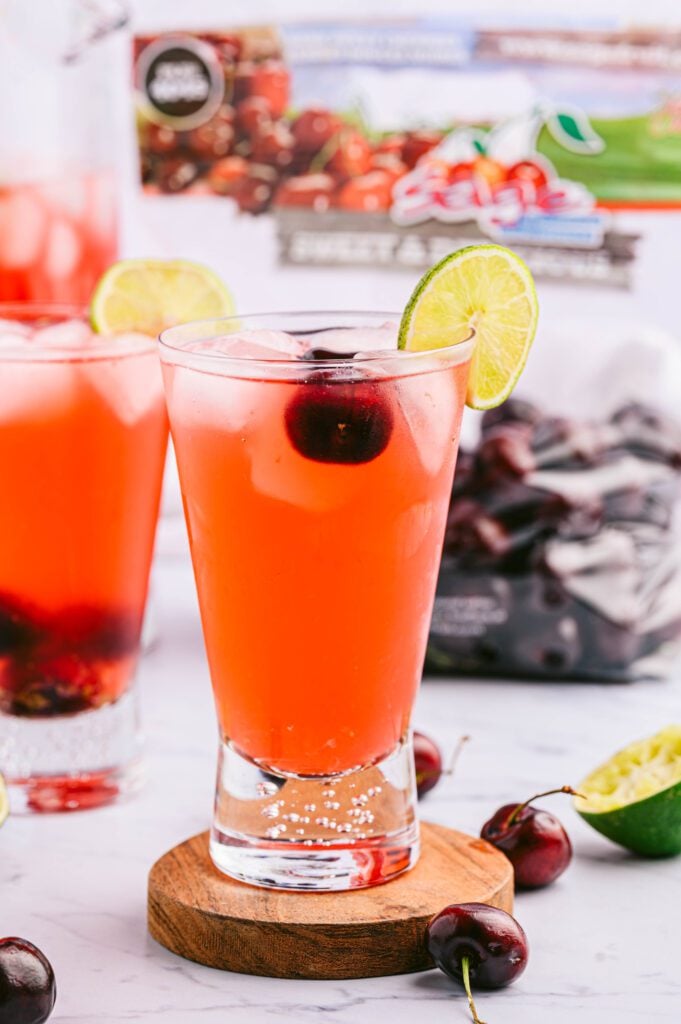 Glass of cherry limeade with cherry bag in back