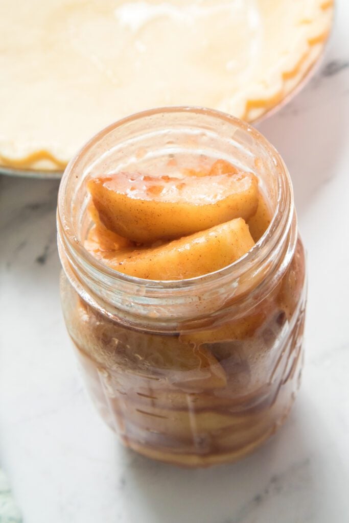 Apple pie filling in mason jar with pie crust in background