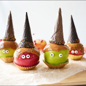 Caramel Apple with Chocolate Witch Hats on a wooden board with parchment paper