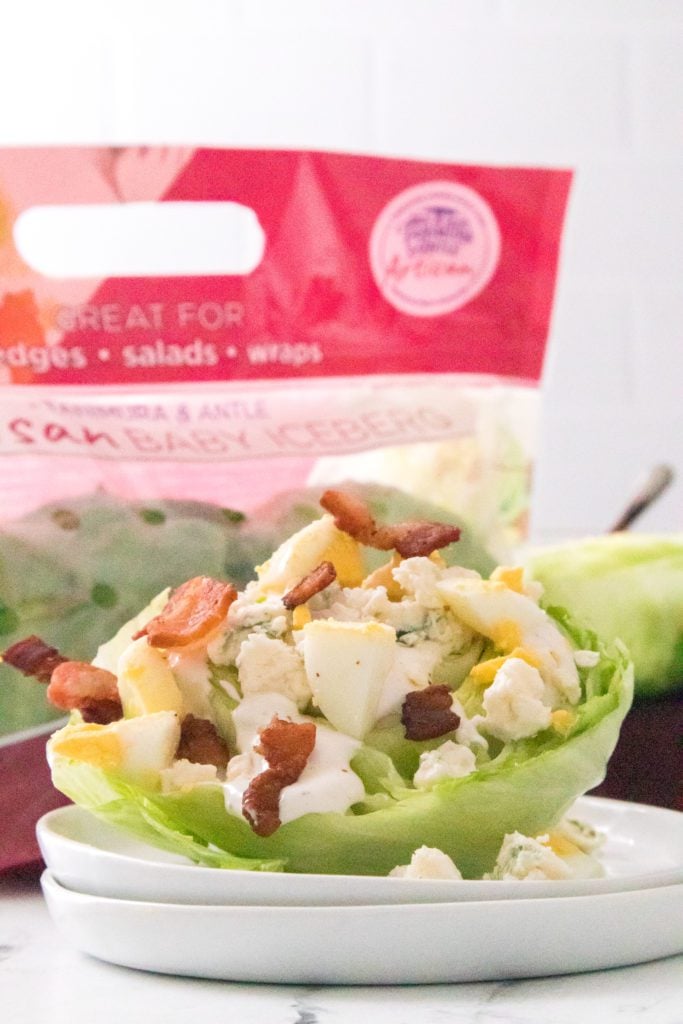 Wedge salad on a plate with lettuce packaging in the background