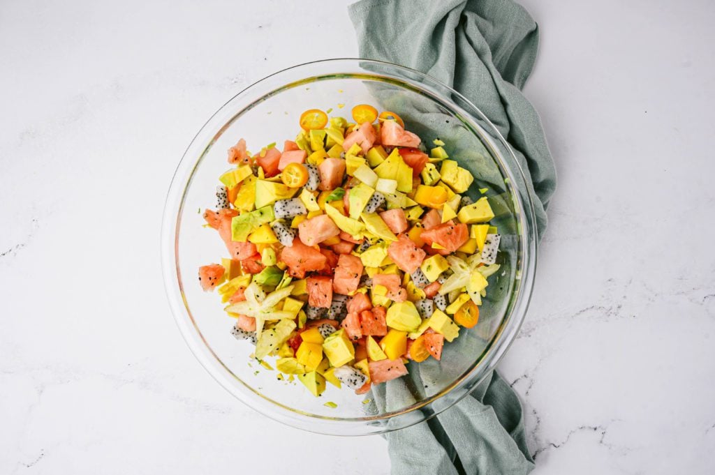 tropical fruit salad mixed together in glass bowl