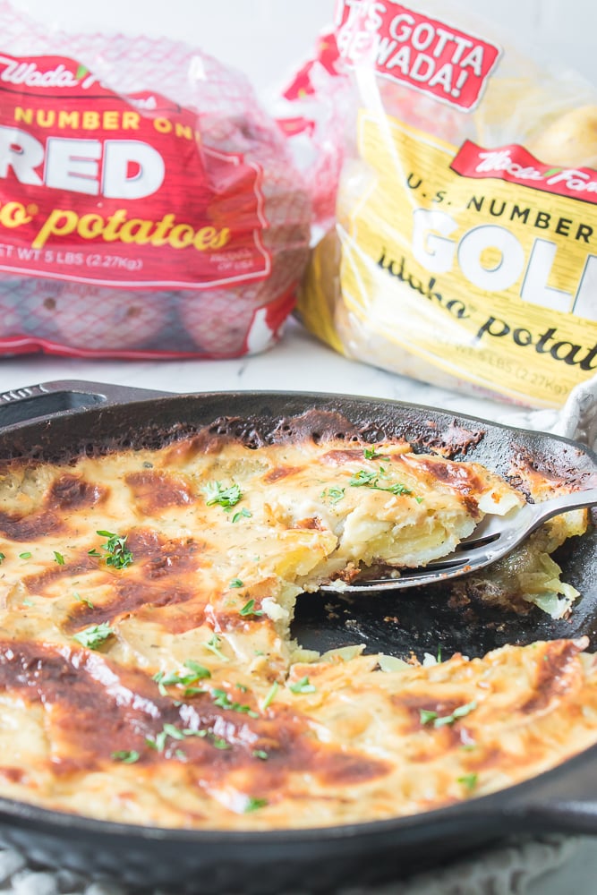 skillet with au grain potatoes with serving spoon and bags of wada farms red and gold potatoes in background