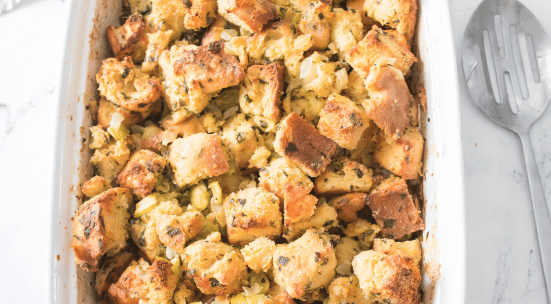 Homemade stuffing in white dish with serving spoon