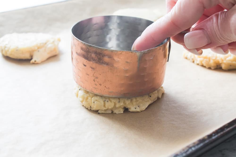 Using a measuring cup to flatten the cookie mixture