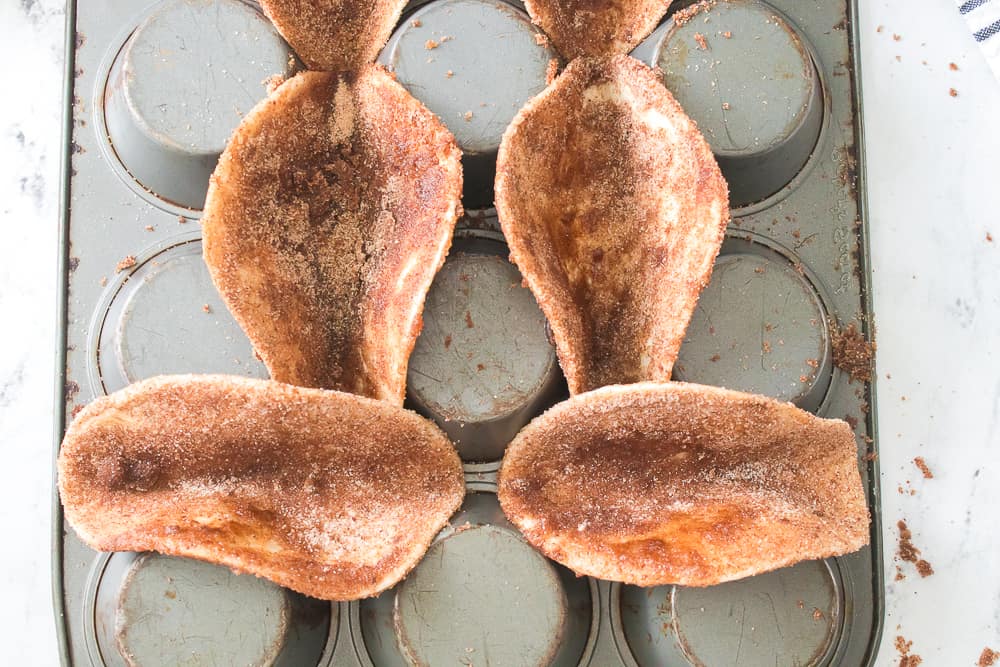 taco shells coated with cinnamon and sugar on an upside down muffin pan