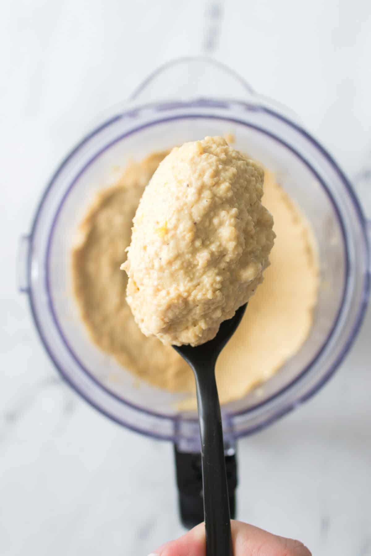 spoonful of hummus over food processor