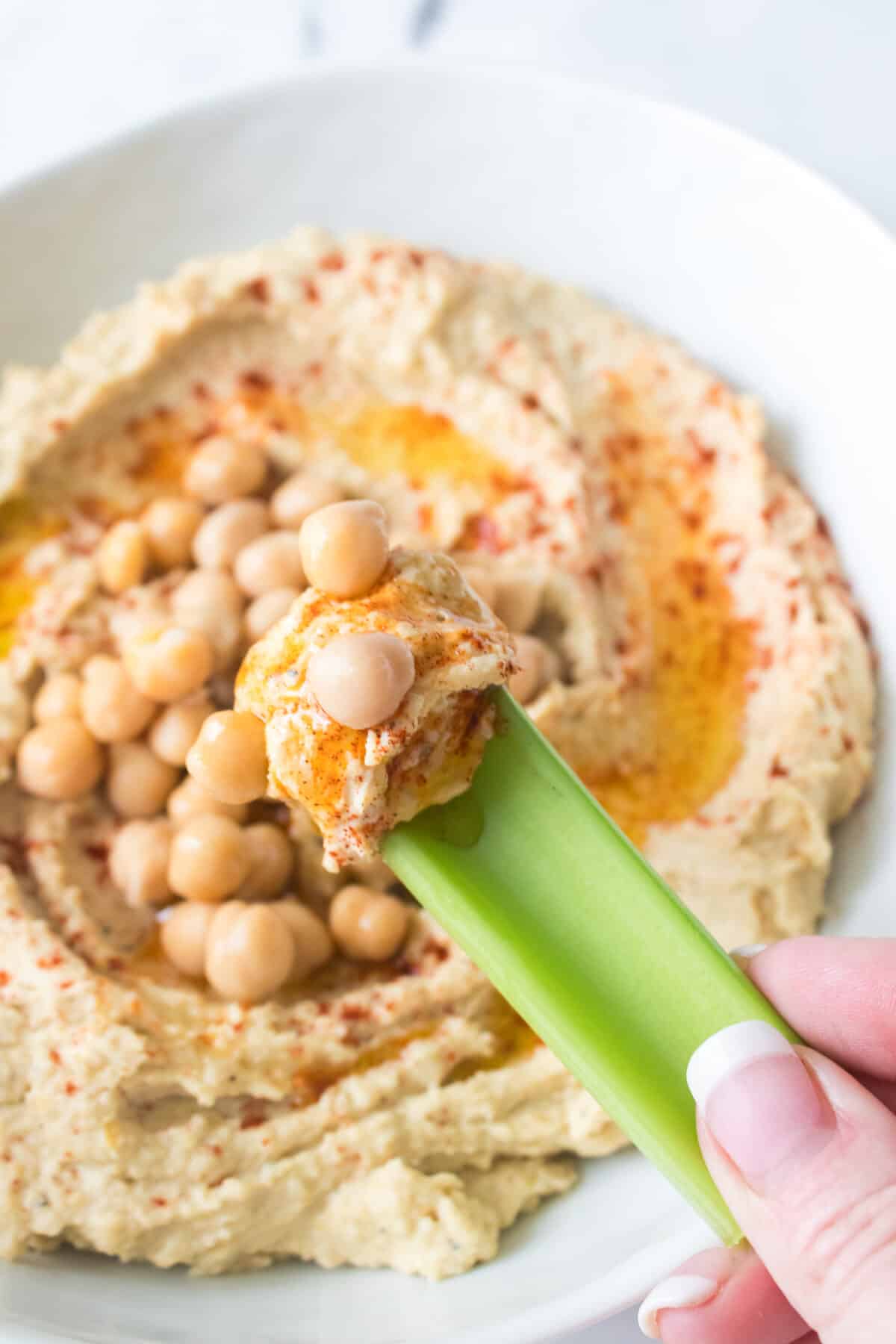 vertical overhead shot of hummus and chickpeas on a piece of celery