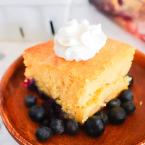 slice of blueberry lemon cake with blueberries in background