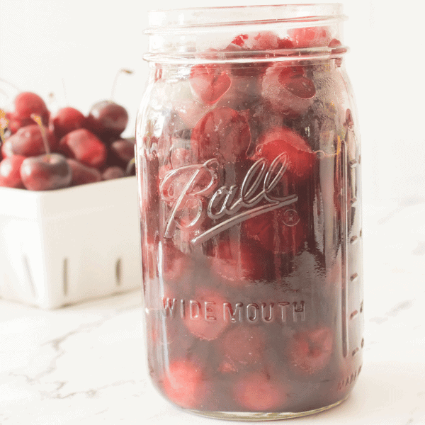 Cherry Pie Filling in mason jar with cherries in background