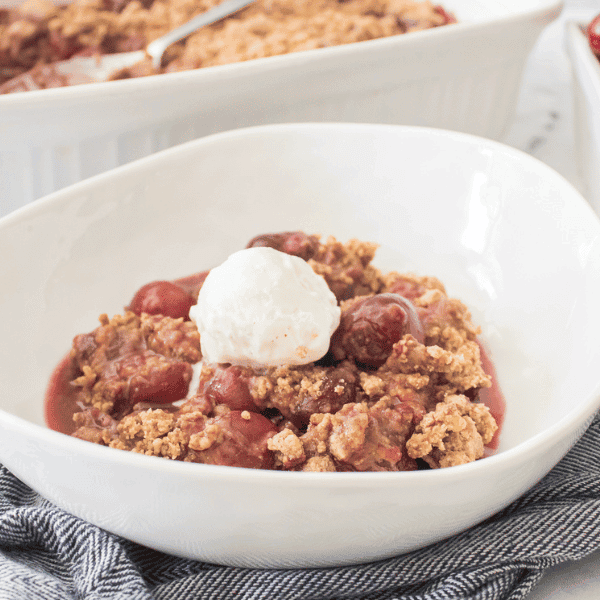 Gluten-Freeh Cherry Cobbler in bowl with cobbler and cherries in background