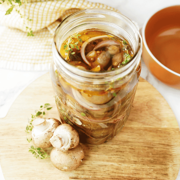 Pickled Mushrooms in bell jar on top of wood board