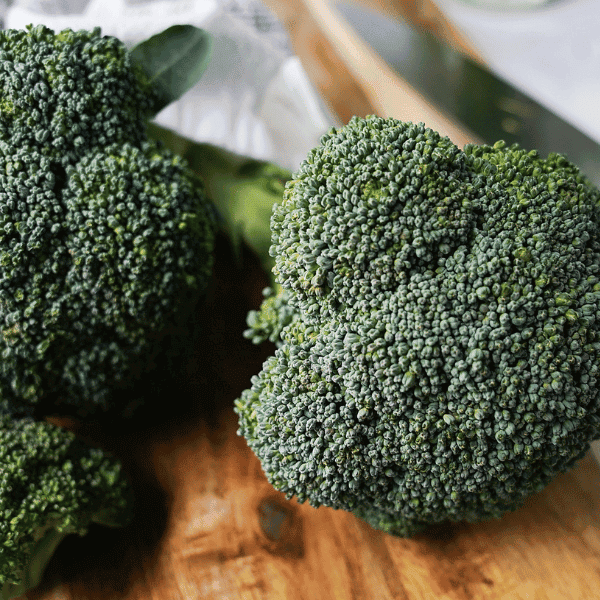 close up of broccoli florets on a wooden cutting board