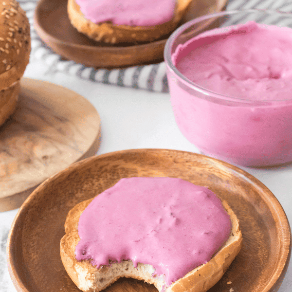 Blueberry Cream Cheese on bagel surrounded by more bagels, blueberries in a bowl and cream cheese in a bowl