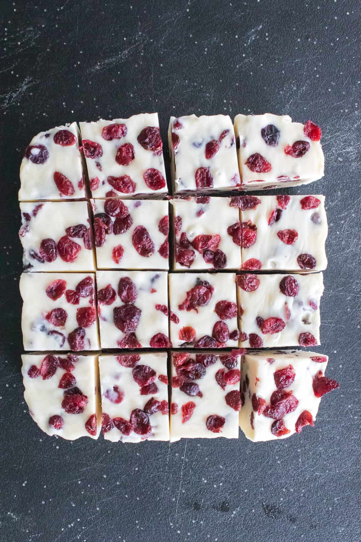 cranberry fudge cut into 16 square pieces on cutting board