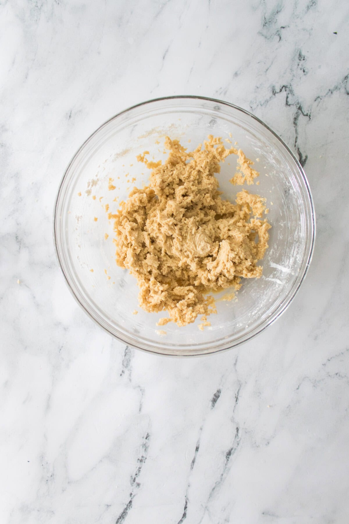 cookie dough mixed together with wet ingredients in glass bowl