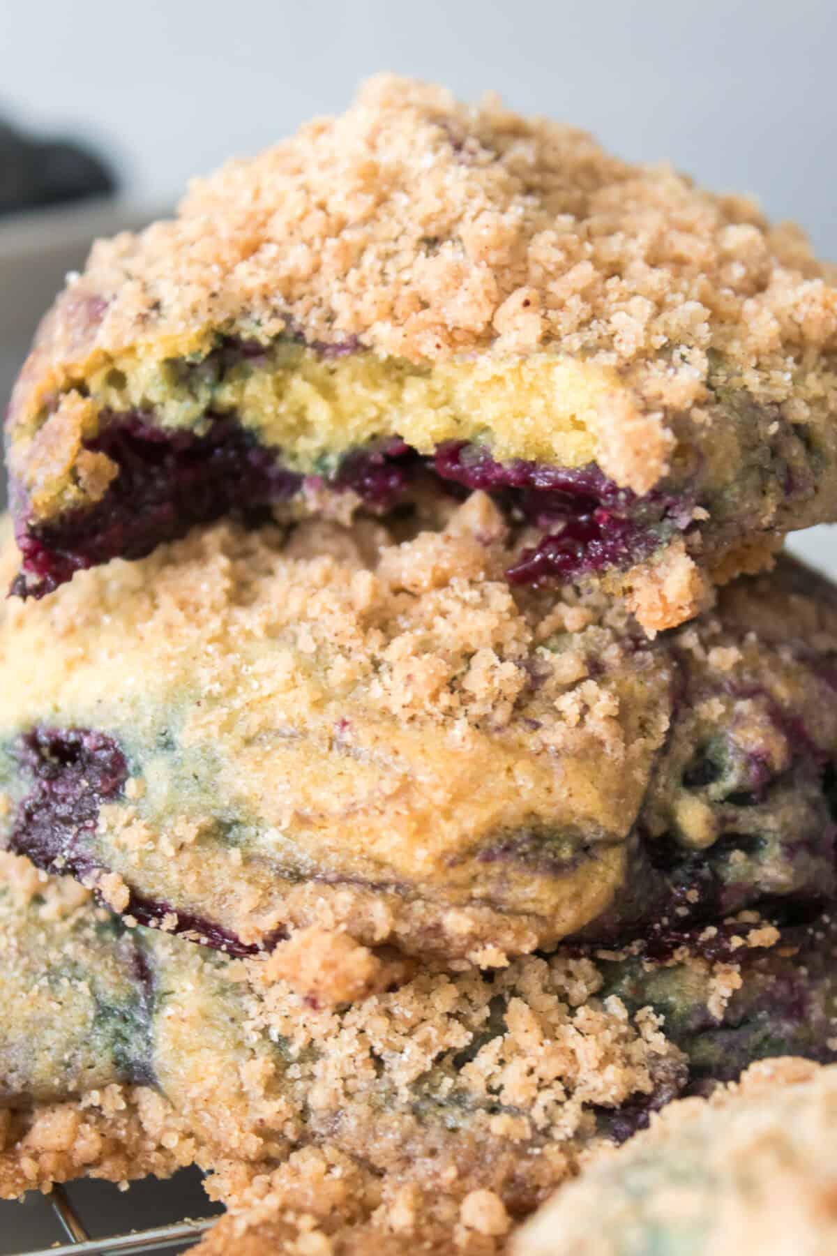 vertical head on shot of bite taken out of Homemade Copycat Crumbl Blueberry Muffin Cookies stacked on top of other cookies