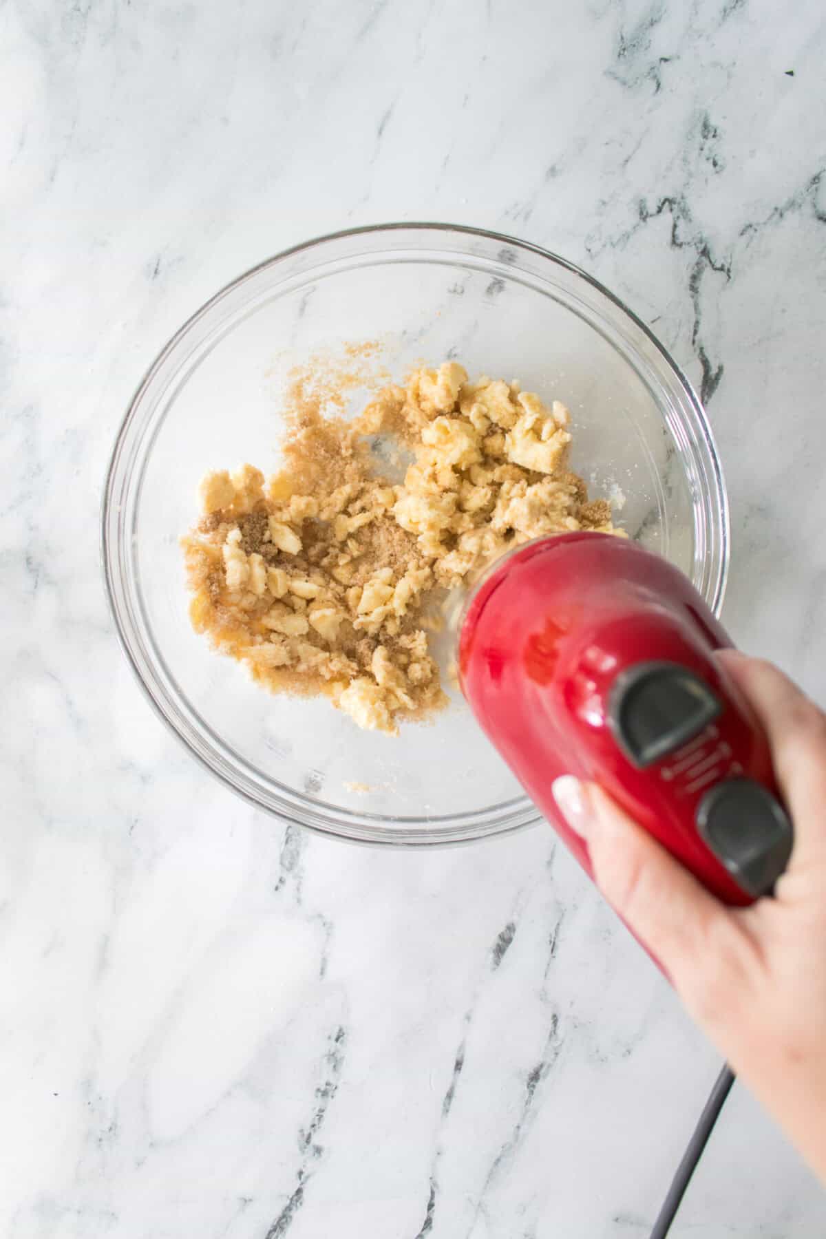 overhead shot of butter, brown sugar and sugar being mixed together with a hand mixer