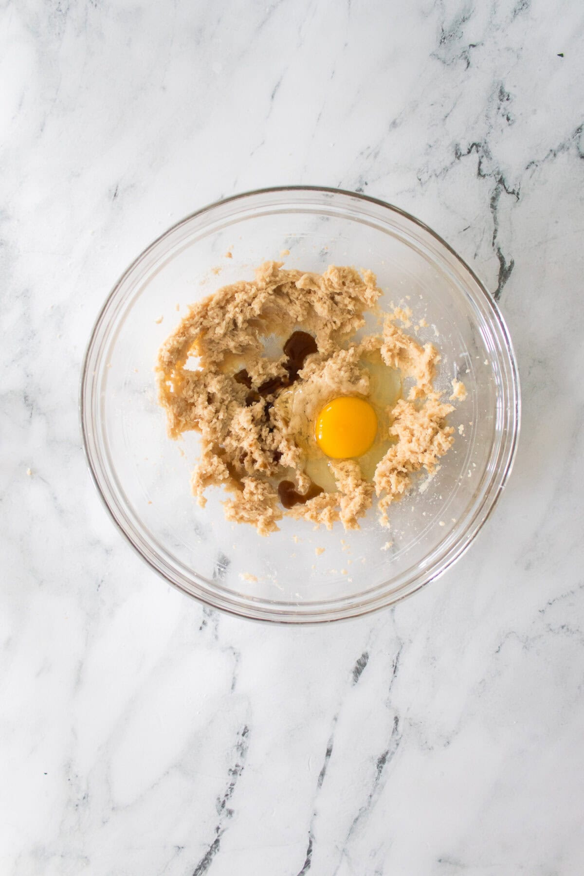 overhead shot of cream and sugars blended together with egg and vanilla extract on top of mixture before being blended