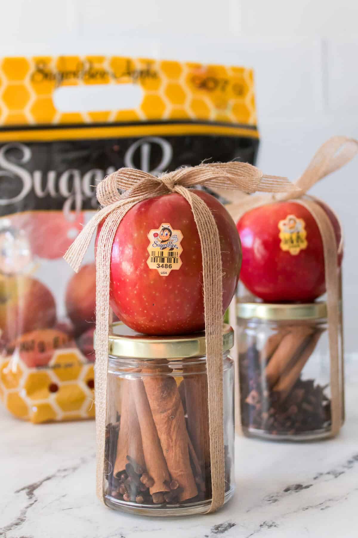 close up head on shot of apple cinnamon potpourri in mason jar with apple tied to jar with jute ribbon