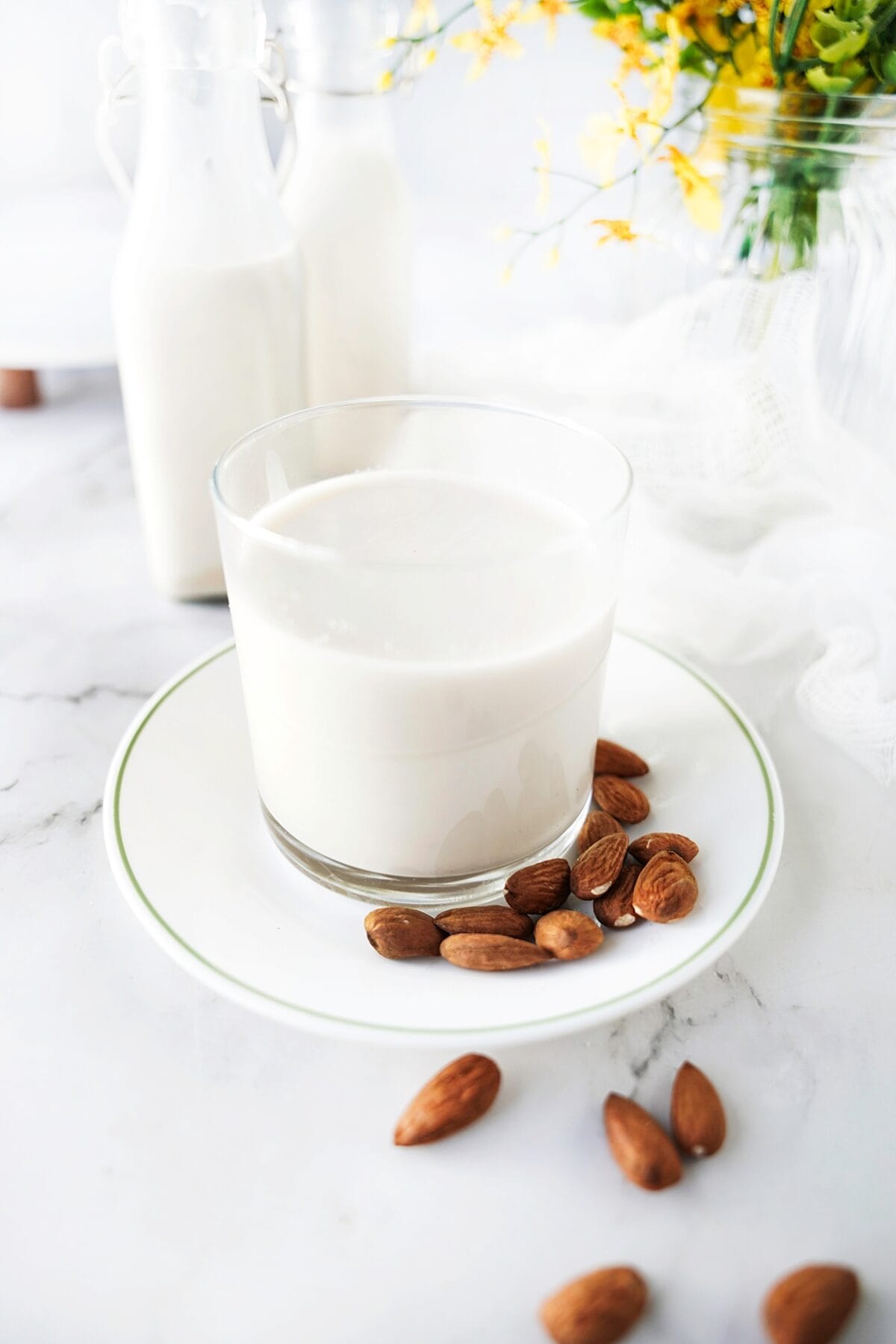 head on shot of glass of almond milk with almond scattered