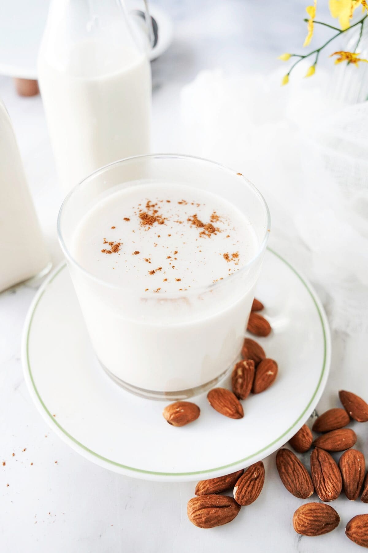 almond milk in glass dish on plate with almonds topped with cinnamon