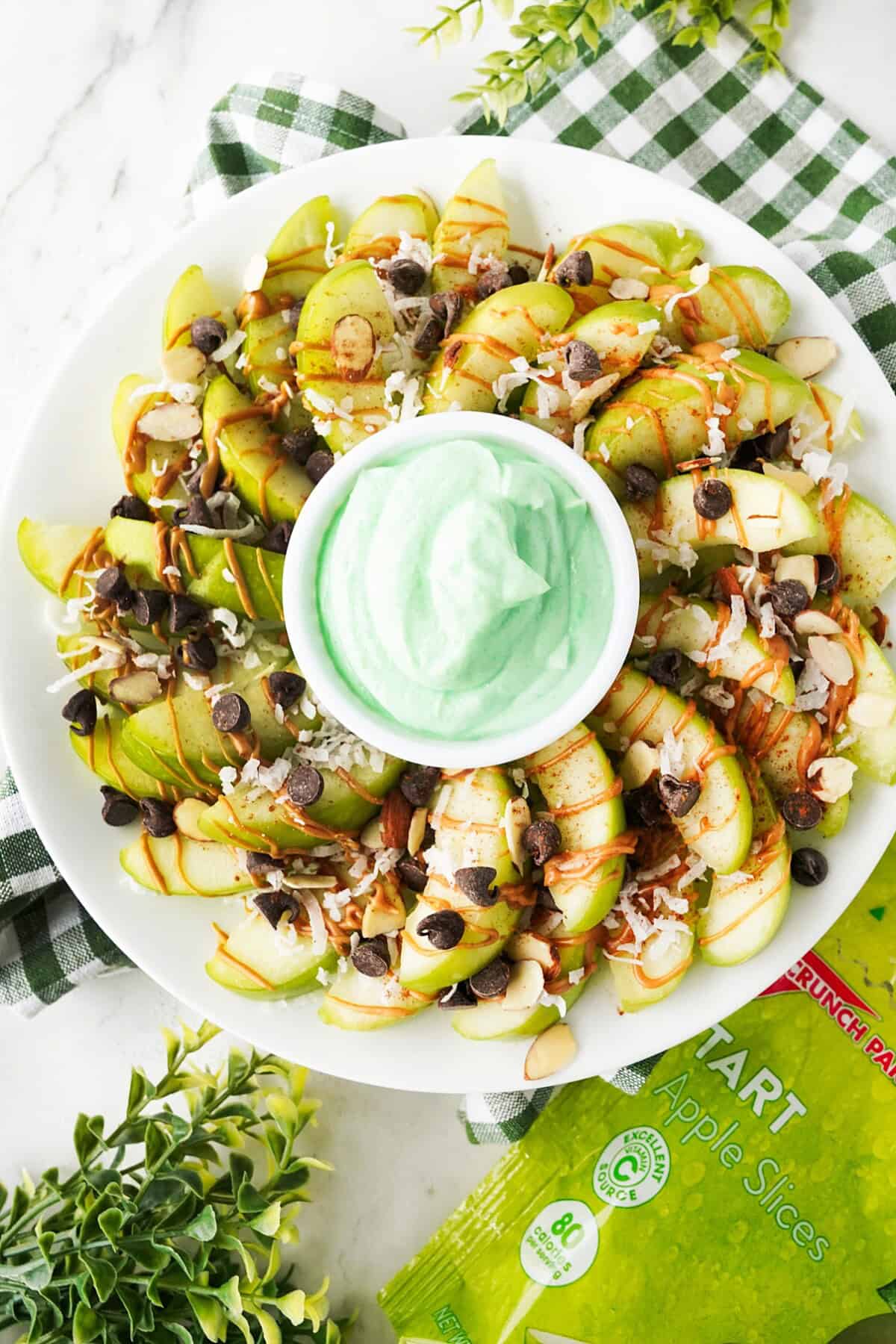 Green apples nachos with green fruit dip on a white plate